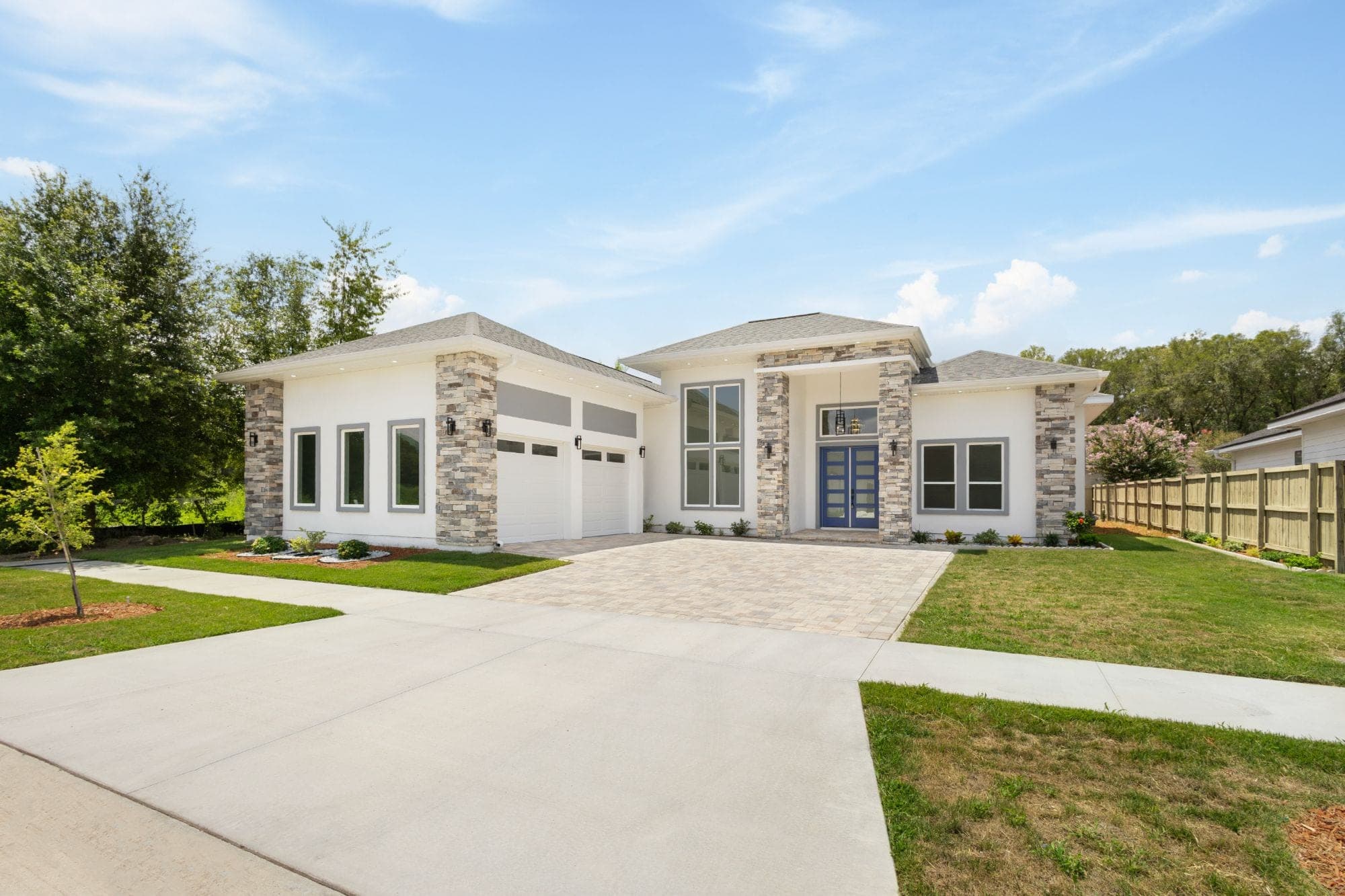 Contemporary stucco home with stone columns and a blue door